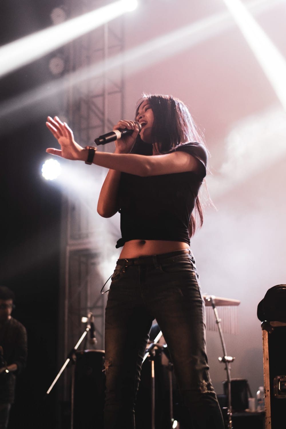 A singer mid-performance, backlit by crossing stage beams.