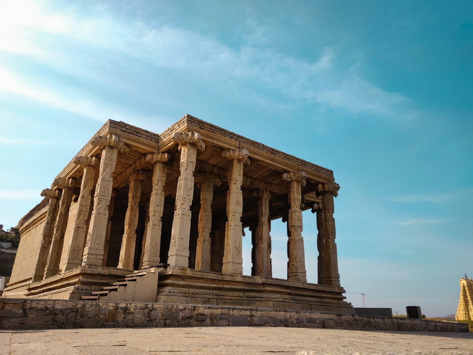 An ancient stone temple with rows of carved columns under a clear blue sky.